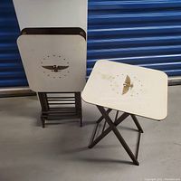 Three vintage snack tables shown, two stacked upright and one unfolded to display the bald eagle design on white top and wooden foldable base.