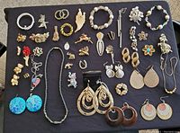 Full display of assorted vintage costume jewelry items in various shapes and colors on a black cloth