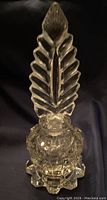 Front view showing the tall feather shaped stopper and detailed cut crystal on the bottle body and base.