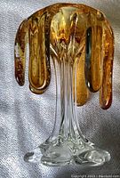 Top view showing amber glass petals and clear glass stem and base, with visible air bubbles inside petals.