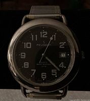 Front view showing Peugeot watch face with black dial, white numerals, and date window.