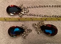 Top view of the teardrop mystic topaz pendant and matching earrings with measuring tape showing pendant size.