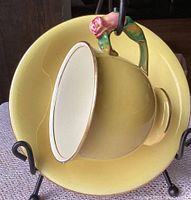 Top view showing butter yellow interior and exterior of teacup and saucer with rosebud detail on handle