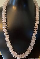 Rose quartz irregular polished chip bead necklace draped on black bust display, showing length and color