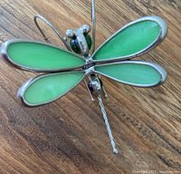 Top view showing green stained glass wings with silver metal frame and twisted wire tail hook.