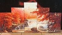 Full view of the five-panel canvas wall art showing vibrant autumn forest, waterfall, and deer scene with red, orange, and brown hues.