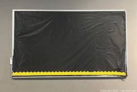 Full frontal view of the mounted bulletin board showing black plastic backdrop with yellow scalloped bottom border.