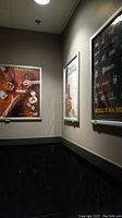 Three silver metal poster grip frames mounted on walls displaying various posters. Frames have clear protective covers and hinged fronts.