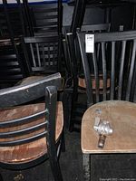 Multiple black metal frame chairs with wooden seats and vertical slat backs, showing wear and signs of use.