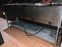 Front and side view of the Bevles industrial kitchen steam table showing three compartments, control knobs, power cord, and stainless steel legs.