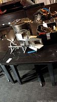 Photo showing the black wooden table base with thick legs and partially visible black granite table top nearby