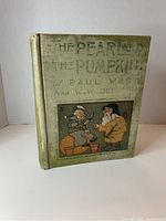 Front cover of 'The Pearland The Pumpkin' book in worn green cloth with illustrated scene and faded text
