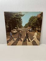 Front cover of The Beatles Abbey Road album showing the iconic crossing scene under daylight on the street with four band members walking.