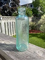 View of antique Boyle & Libby glass bottle outdoors on wooden surface showing embossed logo and shape.