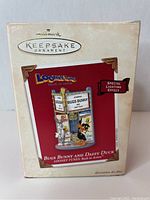 Box of Bugs Bunny and Daffy Duck Hallmark Keepsake ornament, showing front packaging with branding and indication of special lighting effect.