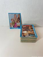 Stack of approximately 44 rectangular Partridge Family cards with blue borders shown upright and in a pile.