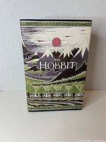 Front cover of The Hobbit limited edition hardcover book with mountains, red sun, and forest illustration.