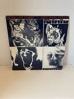 Front cover image of The Rolling Stones Emotional Rescue album showing distinctive black and white artwork divided in four segments with text at the top.