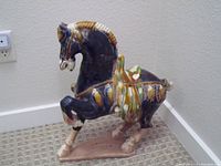 Individual ceramic horse figurine showing detailed glaze and saddle.