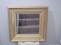 Front view of square wooden framed mirror showing natural wood grain and clean glass surface reflecting carpeted stairs.