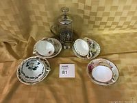 Four floral Royal Albert teacups with matching saucers and the coffee press on a textured golden yellow background.