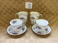 Two tea cups with matching saucers and two coffee mugs arranged to show the floral pattern and shape