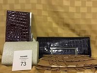 Photo of four clutch purses in black, burgundy, glitter gold, and tan with folded design arranged on a gold textured cloth background.
