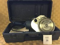 Blue heavy duty electric undercut saw with circular blade inside an open carrying case against a brown background.