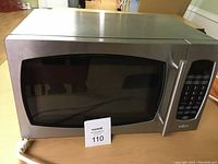 Closed microwave oven showing stainless steel exterior, black window, and digital keypad control on the side