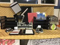 Photo displaying the office supply lot with files, stackers, electronic accessories, and desk items arranged on a table covered with a yellow cloth