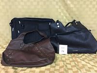 Photo showing three bags: black leather Calvin Klein purse with silver rivet details, brown leather purse with grommet accents, and black fabric computer bag with several zippered pockets.