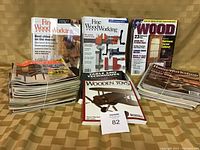 Photo showing stacks of various woodworking magazines including Fine Woodworking, Wood, and Home Workshop titles.