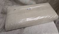 Rolled white waffle patterned non slip rug pad with label 80 x 60 inches visible, wrapped in plastic
