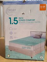 Front of the boxed memory foam bed topper showing brand, size, and features.