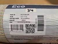 Close-up image of the rolled rug label showing size 2'3" x 7'3", color gray, material 100% polypropylene, made in Turkey.