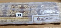 Photo of wrapped Gloria rug with brand label and lot number 37