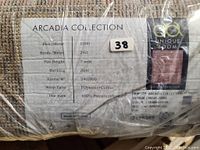 Close-up photo of the rug label showing detailed product specifications including pick density, pile height, backing type, knot density, and yarn materials for the Arcadia Collection rug.