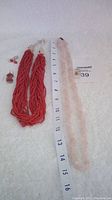 Coral bead necklace, pink stone necklace, and two pairs of earrings shown with measuring tape.