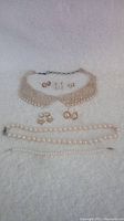 Overview of the full lot including pearl collar necklace with filigree clasp, various pairs of pearl and gold earrings, pearl bracelet, and pearl necklace strands.