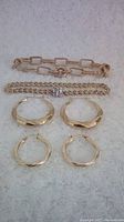 All items arranged: two bracelets at top and two pairs of hoop earrings below.