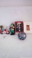 Lot showing all ornaments displayed together: three glass ornaments and two Hallmark boxed ornaments