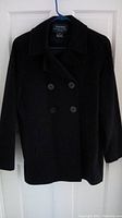 Front full view of the black Ralph Lauren peacoat hanging on a door showing double-breasted button closure and collar.