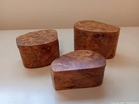 Three closed burl wood trinket boxes of varying sizes arranged on a flat surface, showing the polished tops with visible wood grain patterns.