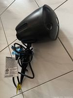 Black outdoor projector light unit with power cord and label, about 10 inches tall