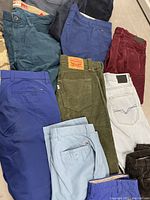 Eight folded pants showing assorted colors and corduroy texture