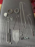 Top view of all items showing necklaces, earrings, bracelet, and pendant arranged on dark surface