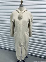 Front full view of the vintage ivory La Parka coat on a mannequin in front of a corrugated metal background.