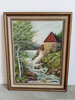 Framed oil painting of a waterwheel mill next to waterfall and flowing stream