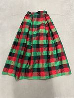 Full front view of the silk iridescent checkered Christmas skirt laid flat showing its length and checkered pattern with red, green, and black squares.