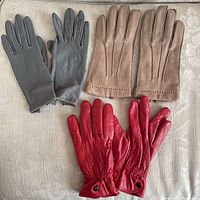 Three pairs of vintage leather ladies gloves arranged on fabric surface, showing front sides and details.